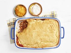 a casserole dish with cheese and other toppings on the side next to it