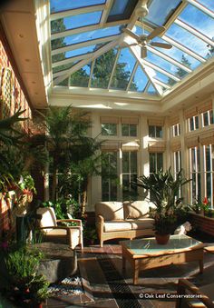 a sun room filled with lots of windows and plants on the tables in front of it