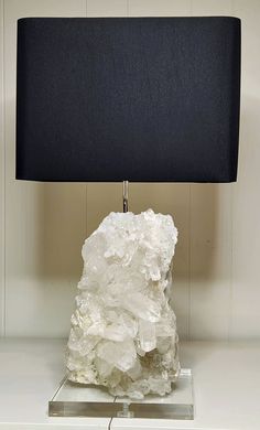 a lamp that is on top of a white table with a black shade over it