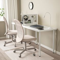 a white desk with two chairs and a clock on the wall in front of it