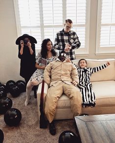 a group of people sitting on top of a couch in a living room next to each other