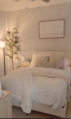 a bedroom with a white bed and a tree in the corner