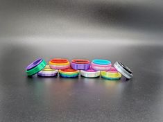 several different colored rings sitting on top of a black table next to a metal container