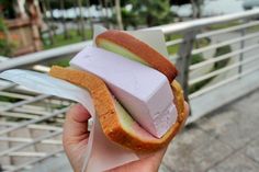 a person holding a sandwich with marshmallows and cucumber on it