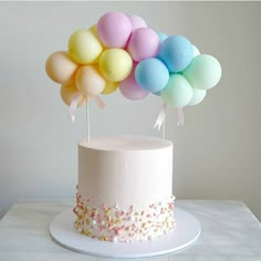 a white cake topped with balloons on top of a table