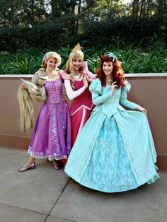 three girls dressed up as princesses posing for the camera