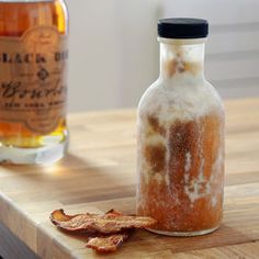 a bottle of alcohol sitting on top of a wooden table next to a glass jar