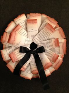 a paper plate with black ribbon and some pieces of book pages in the shape of a circle