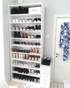 a white shoe rack filled with lots of shoes next to a door in a room