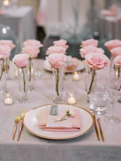 the table is set with pink roses and place settings