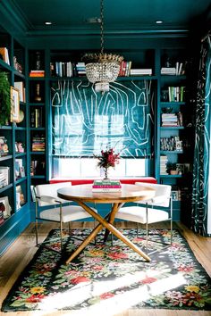 a room with bookshelves, chairs and a table in the middle of it