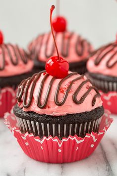 chocolate cupcakes with pink frosting and a cherry on top are ready to be eaten