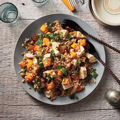 a plate filled with rice and vegetables on top of a wooden table next to utensils