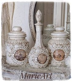 three white vases sitting on top of a table next to a mirror and curtain