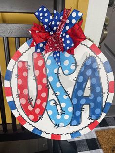 a patriotic door hanger with the word usa painted on it and polka dot ribbon