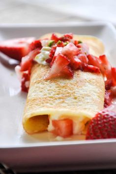 a crepe filled with strawberries on top of a white plate