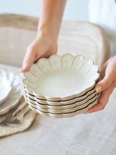 a person holding a stack of plates on top of a table