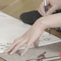 a person writing on a piece of paper with a pen and eyeglasses next to it