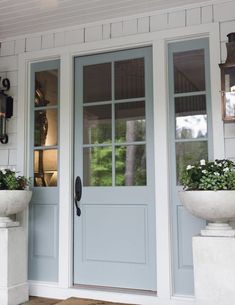 a blue front door with two planters on either side