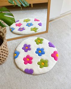 two round rugs with flowers on them next to a mirror and plant in a basket