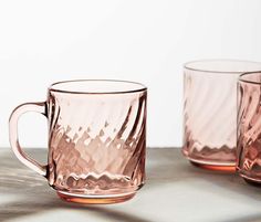 two pink glass mugs sitting next to each other