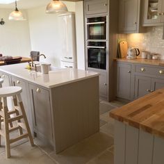 a kitchen with two stools and an island in the middle, surrounded by gray cabinets