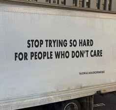 a white truck with black lettering on the side driving down a street next to tall buildings