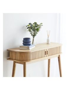 a wooden table topped with a blue vase next to a plant