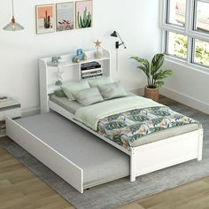 a white bed sitting next to a window on top of a hard wood floored floor