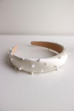 a white headband with pearls on it sitting on top of a table next to a wall