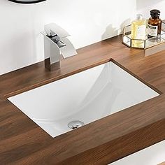 a bathroom sink sitting on top of a wooden counter next to a mirror and soap dispenser