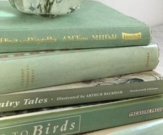 three books stacked on top of each other with a glass ball sitting on top of them