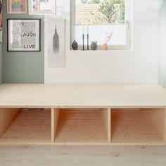 a wooden bench sitting in the middle of a room with pictures on the wall behind it