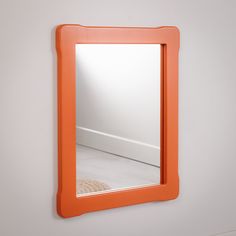 an orange mirror mounted to the side of a wall