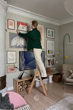 a woman standing on a ladder in front of a tv