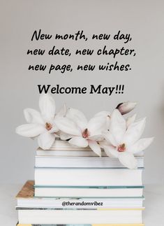 a stack of books with white flowers sitting on top of each other next to a sign that says new month, new day