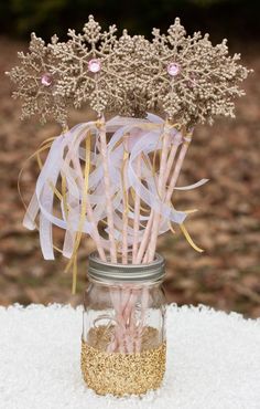 a mason jar filled with pink and gold straws sitting on top of snow covered ground