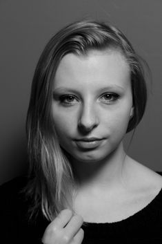 a black and white photo of a woman with long blonde hair wearing a sweater looking at the camera