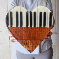 a person holding a wooden heart with piano keys