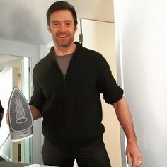 a man holding a hair dryer in his hand and standing next to a mirror