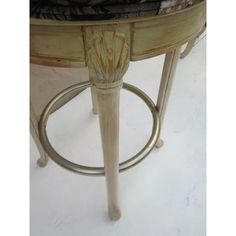 an old stool with a wooden seat and metal ring around the footrests, on a white floor