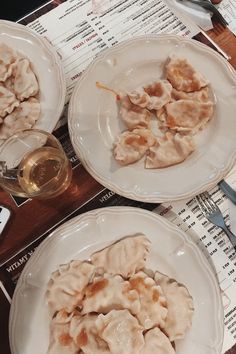 two white plates topped with dumplings on top of a table next to silverware