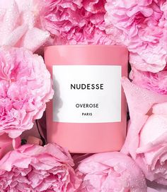 pink flowers surrounding a candle that says nudgesse overrosee paris on it