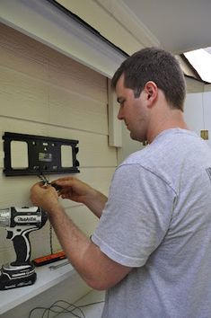 a man is working on a wall with a drill and screwdriver in his hand