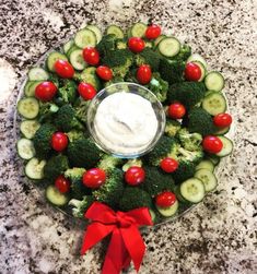 a platter filled with cucumbers, tomatoes and broccoli topped with ranch dressing