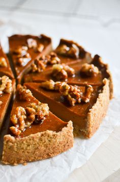 a close up of a pie on a piece of paper with walnuts and pecans