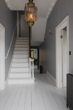 an empty hallway with stairs and a chandelier hanging from it's ceiling