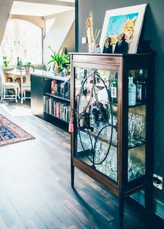 an image of a glass cabinet in the middle of a room with pictures on it