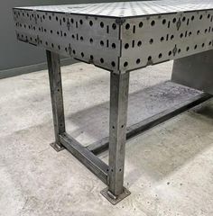 a metal workbench with holes on the top and bottom, sitting in a room