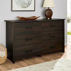 a brown dresser sitting in a living room next to a lamp